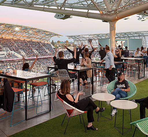 group of people sitting on the sunset deck of the stadium enjoying the game